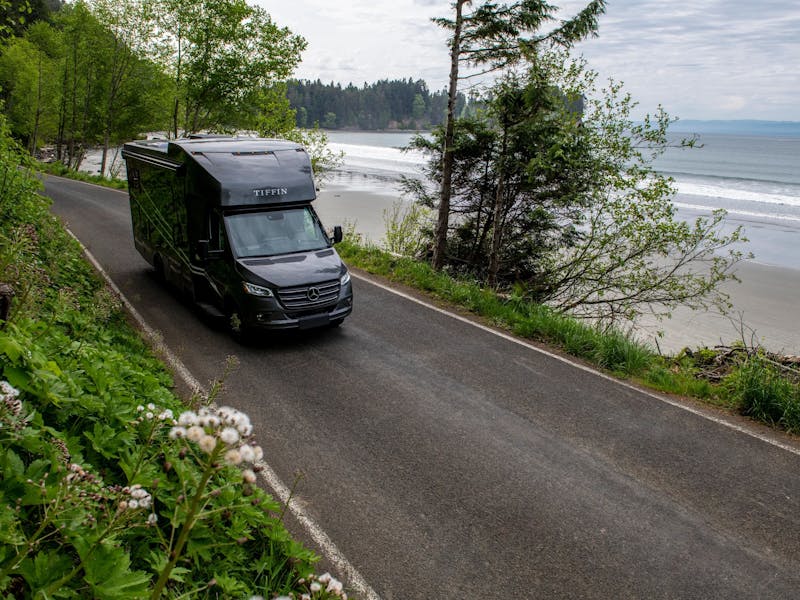 A tiffin wayfarer class C rv driving down the road next to the ocean