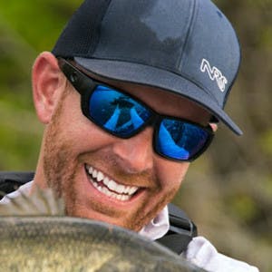 A headshot of Robert Field smiling as he holds a fish.