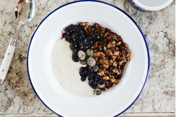 Bowl of hemp granola with blueberries on a tabletop.