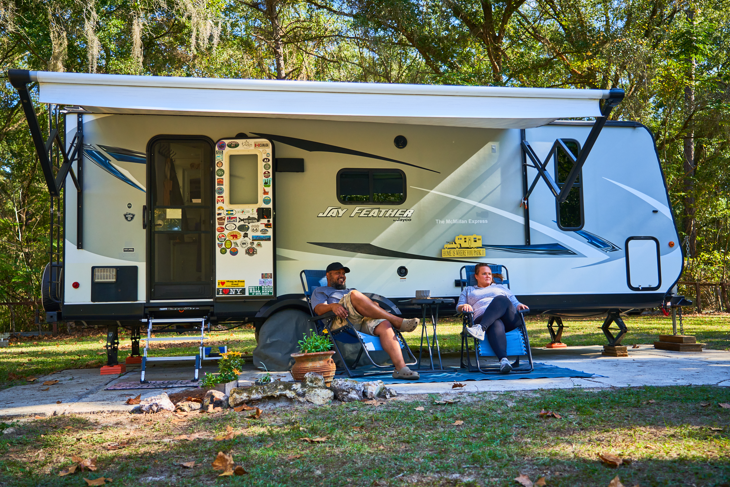 Ben and Christina McMillan lounging in front of their Jay Feather travel trailer