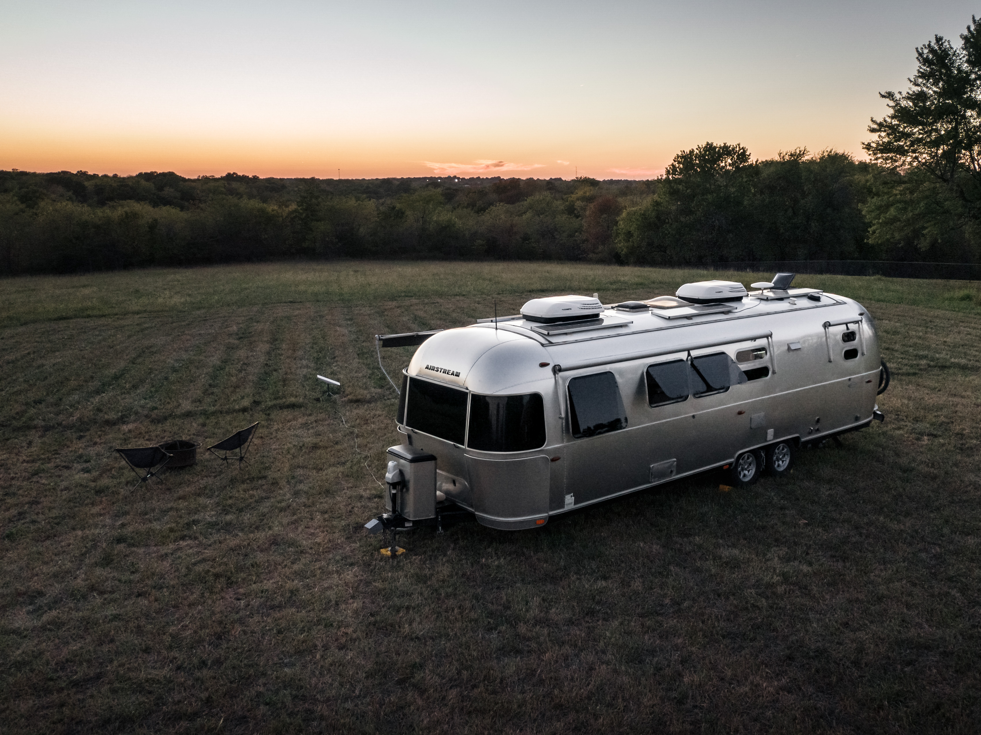 Karen Blue's airstream boondocking in a field at dusk