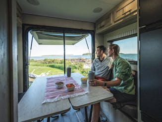 A couple enjoys the view from the dinnette of a KZ Escape travel trailer