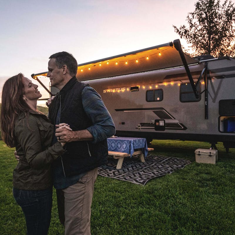 A couple dances next to their Venture RV Stratus during sunset.