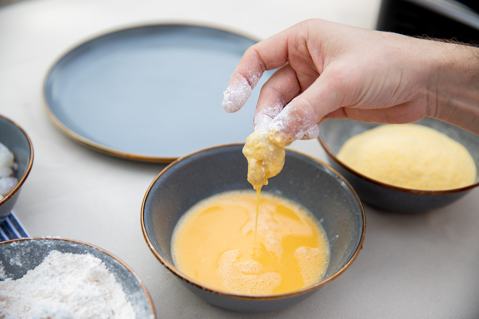 Coating shrimp in batter before frying.
