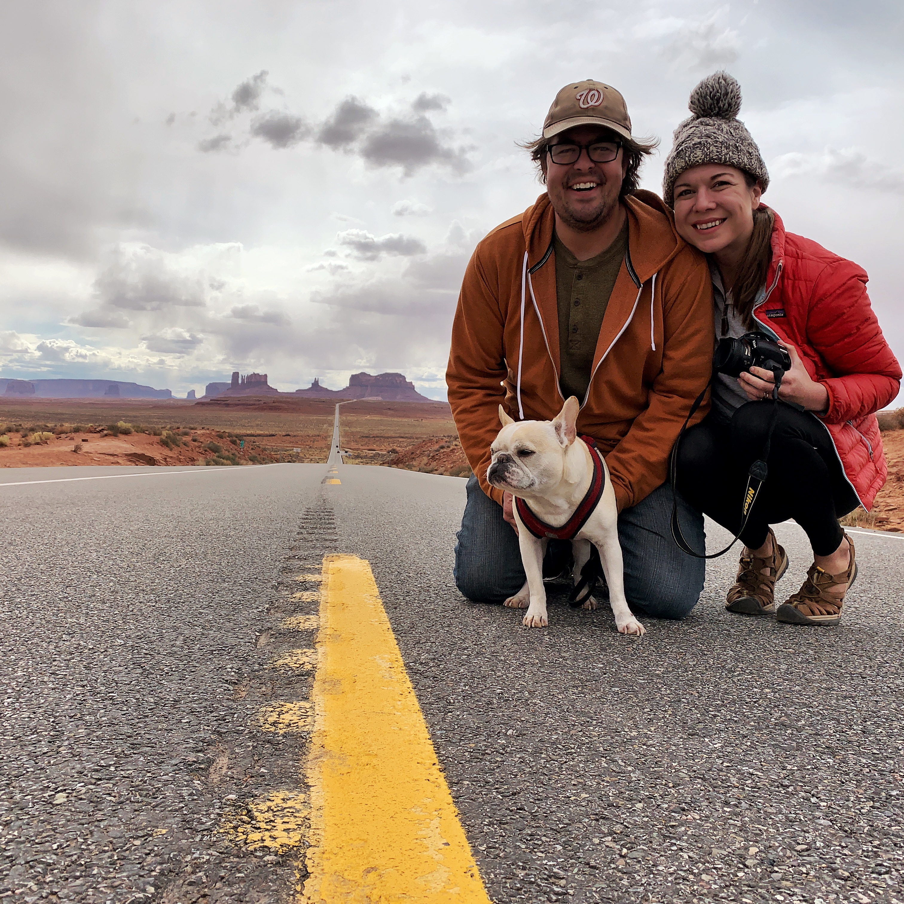 Sarah Hubbart, her husband and their dog take a photo in the road in the desert. 