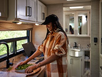 Travel writer Adrienne Jordan cooks dinner inside a Thor Motor Coach Gemini Class B+ Motorhome.