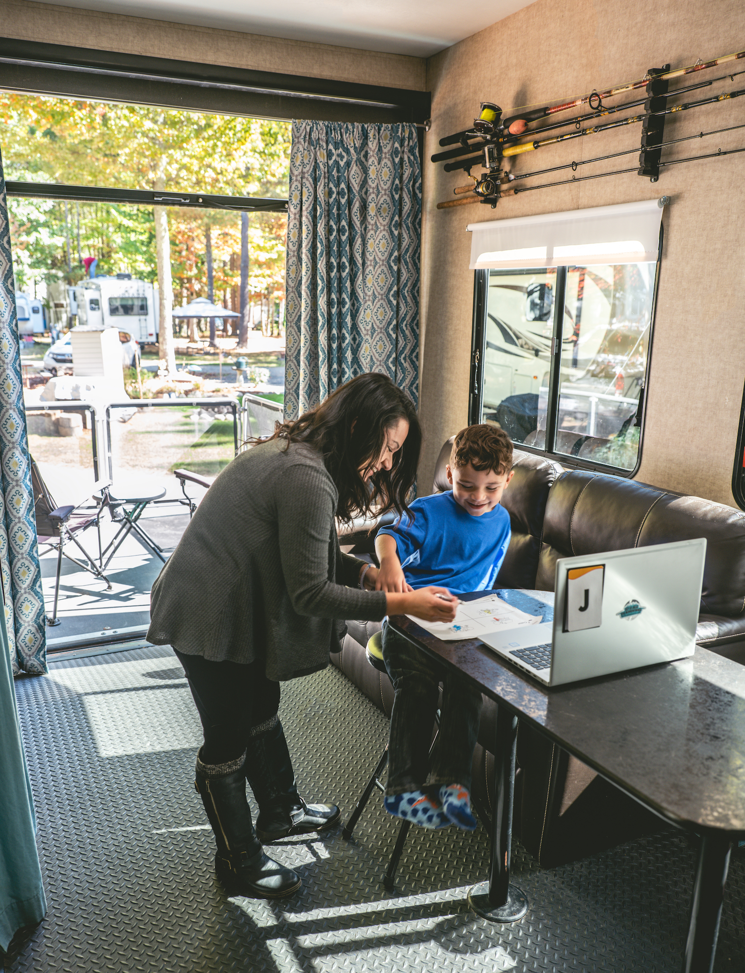 Sandra standing over her son at a desk in the converted garage space. 