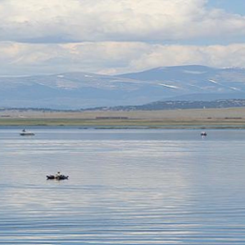 Still waters dotted with small boats and mountains in the far distance.