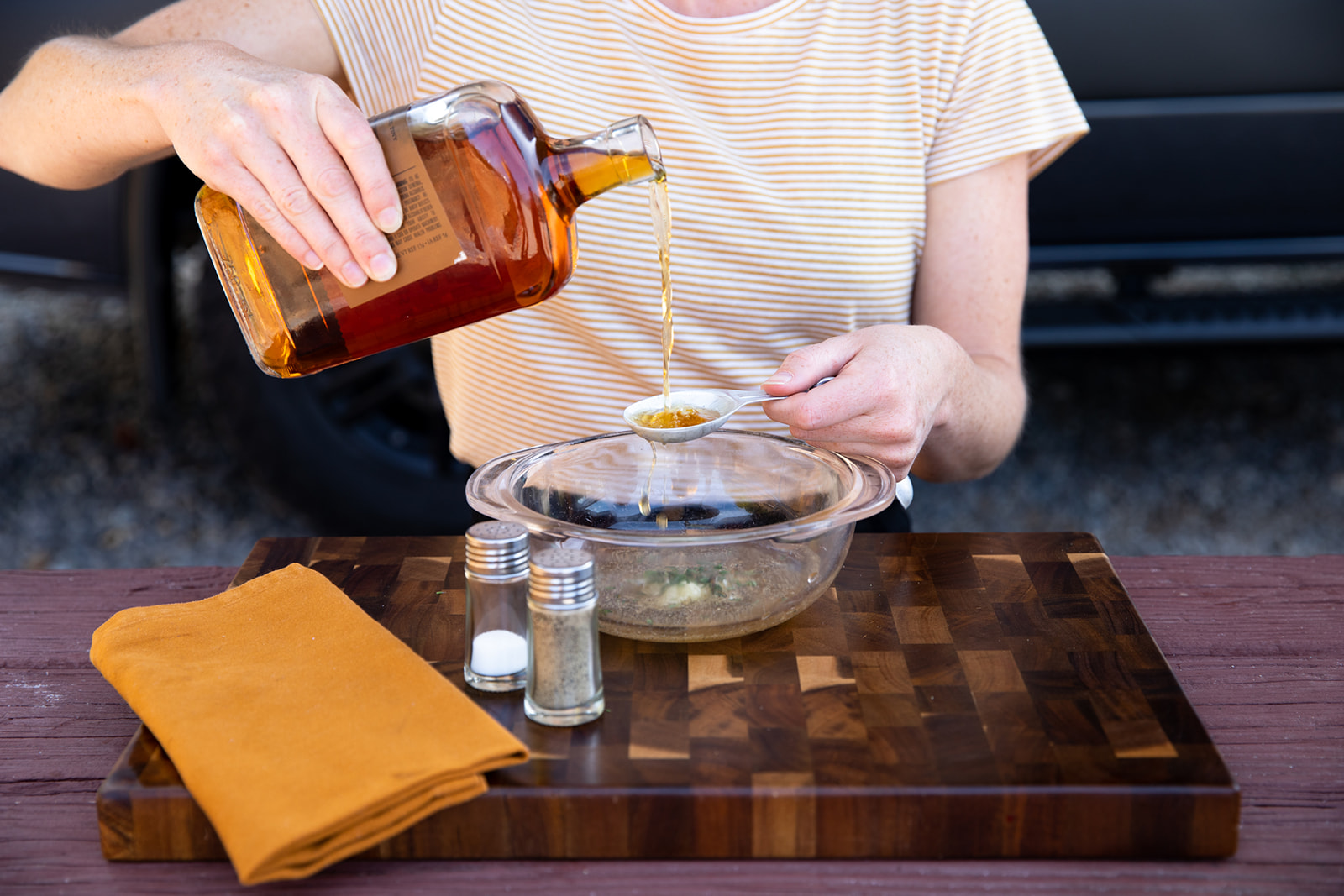 A woman pours whiskey into a measuring spoon.