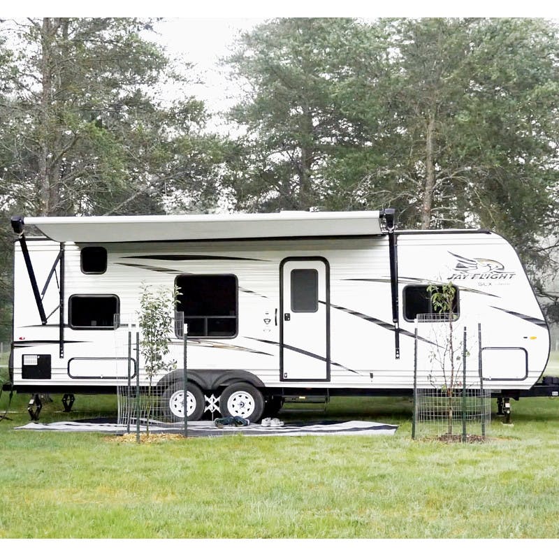Exterior shot of a Jayco Travel Trailer parked outside in a forest. 
