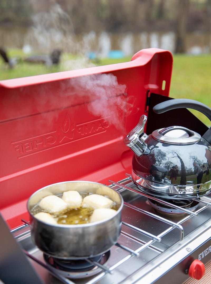 Heating water for coffee while beignets fry in a pot of oil.