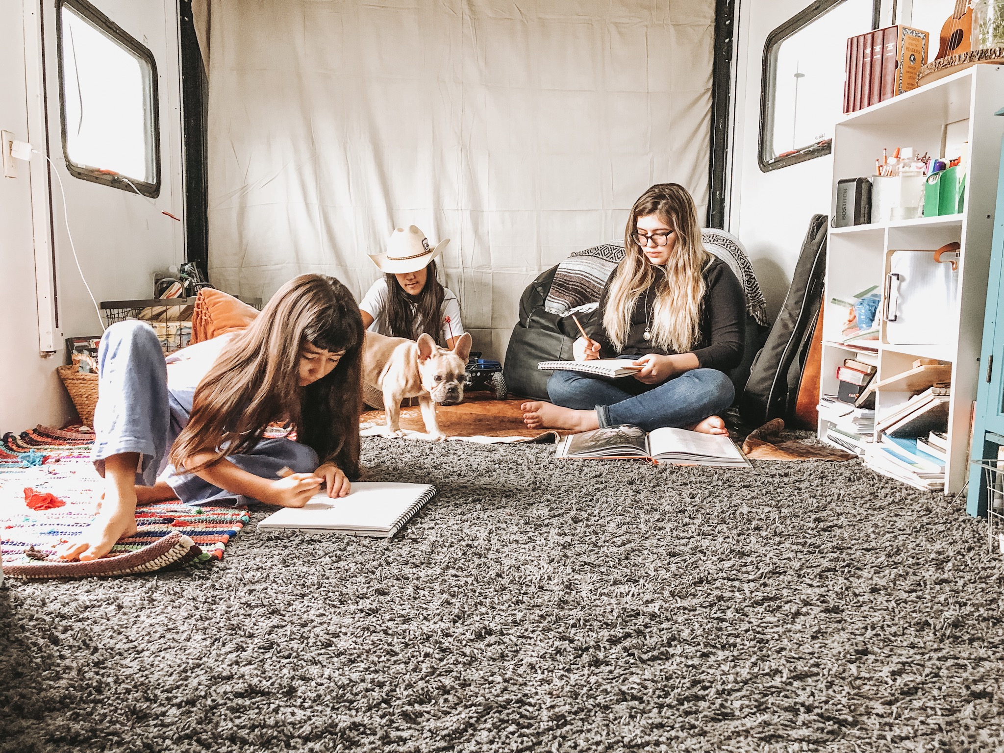 Three kids and a dog sitting in a cozy room in an RV. 