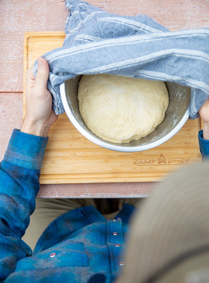 Letting dough rise in a bowl covered with a towel.