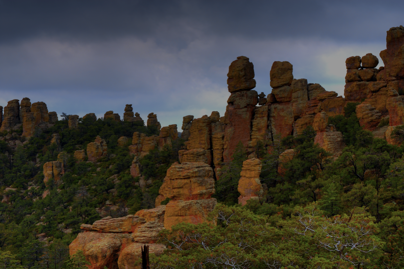 Tall, red Chiricahua mountains stacked on top of each other, surrounded by green trees
