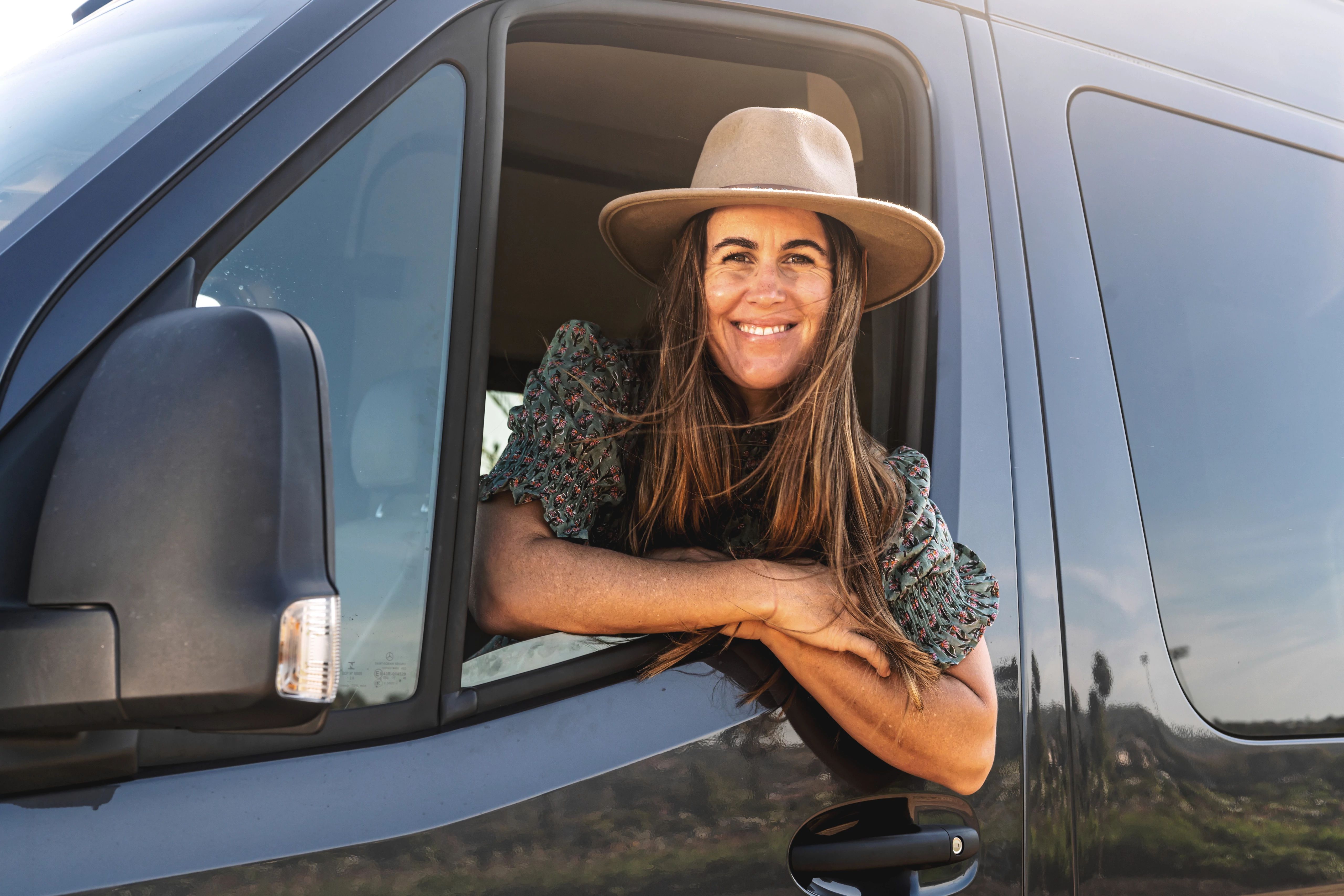 Sarah Glover smiling out of the window of a TMC Tranquility camper van.