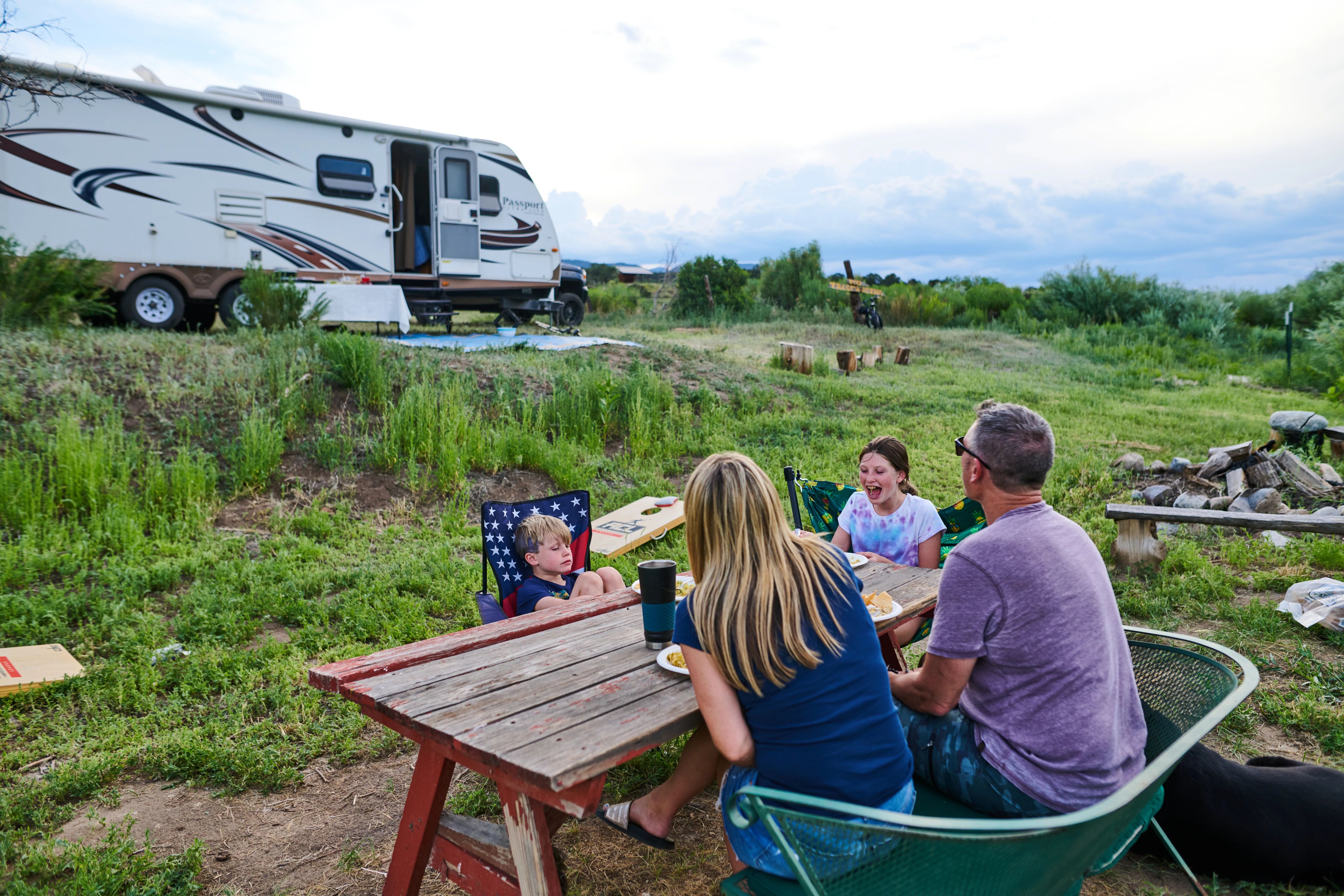 Chris Heublein's family eating a meal at a wooden table outside of their RV