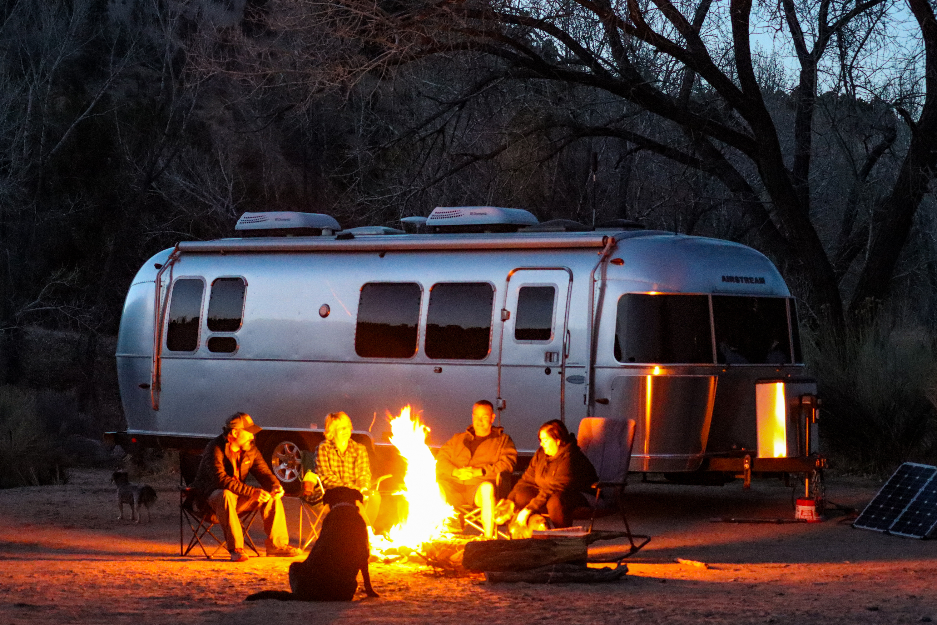 Greg Graham and friends sit at a campfire in front of his Airstream.