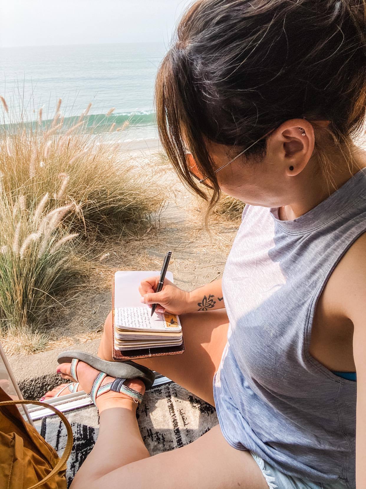 Jess Lawson journaling while sitting in the doorway of her class B RV, a Thor Motor Coach Tellaro.