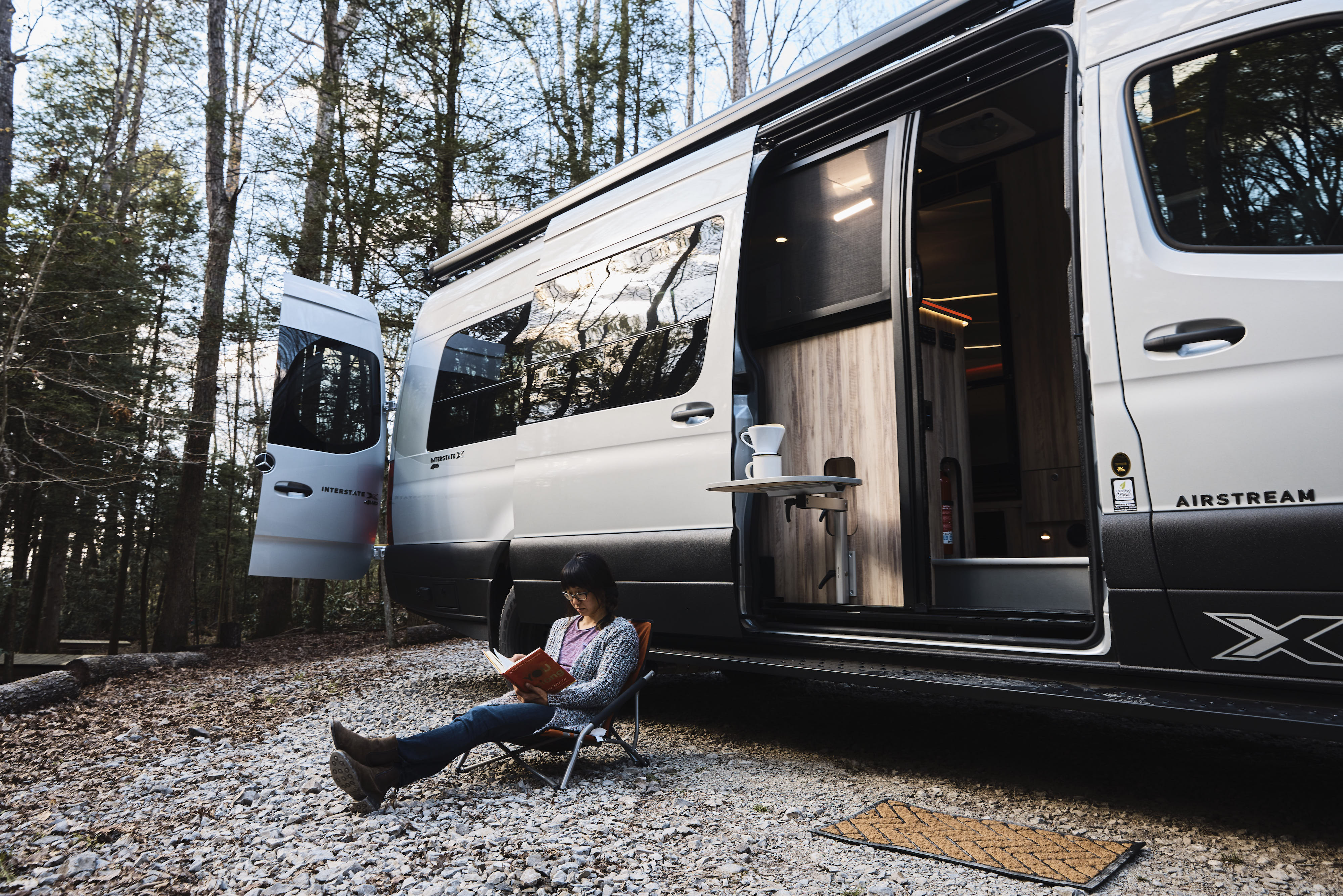 Kathy Karlo reading outside of an Airstream Camper Van
