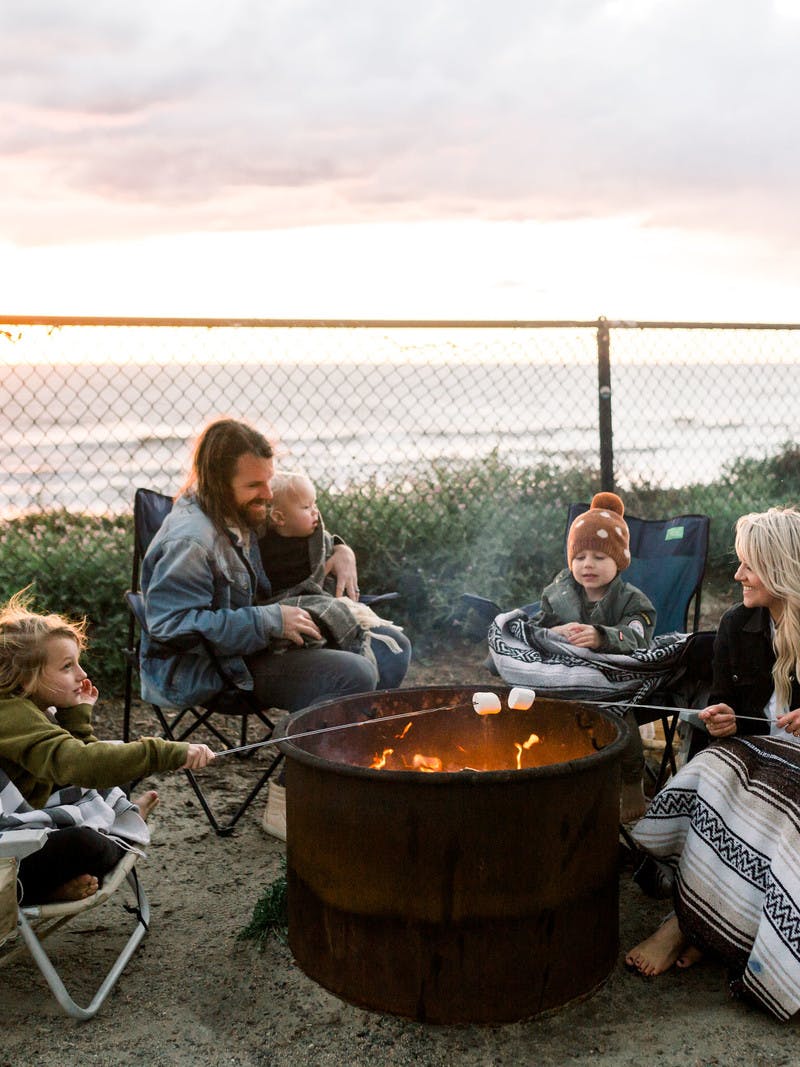 Amber Thrane and her family roasting marshmallows over a fire by an Airstream Travel Trailer RV
