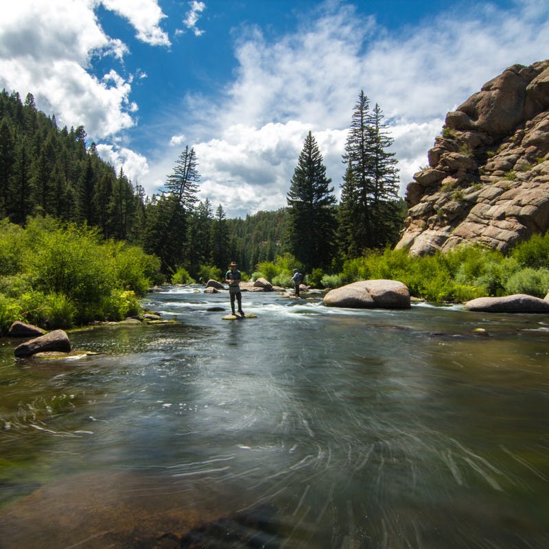 Marshall standing in clear river water as he fishes.