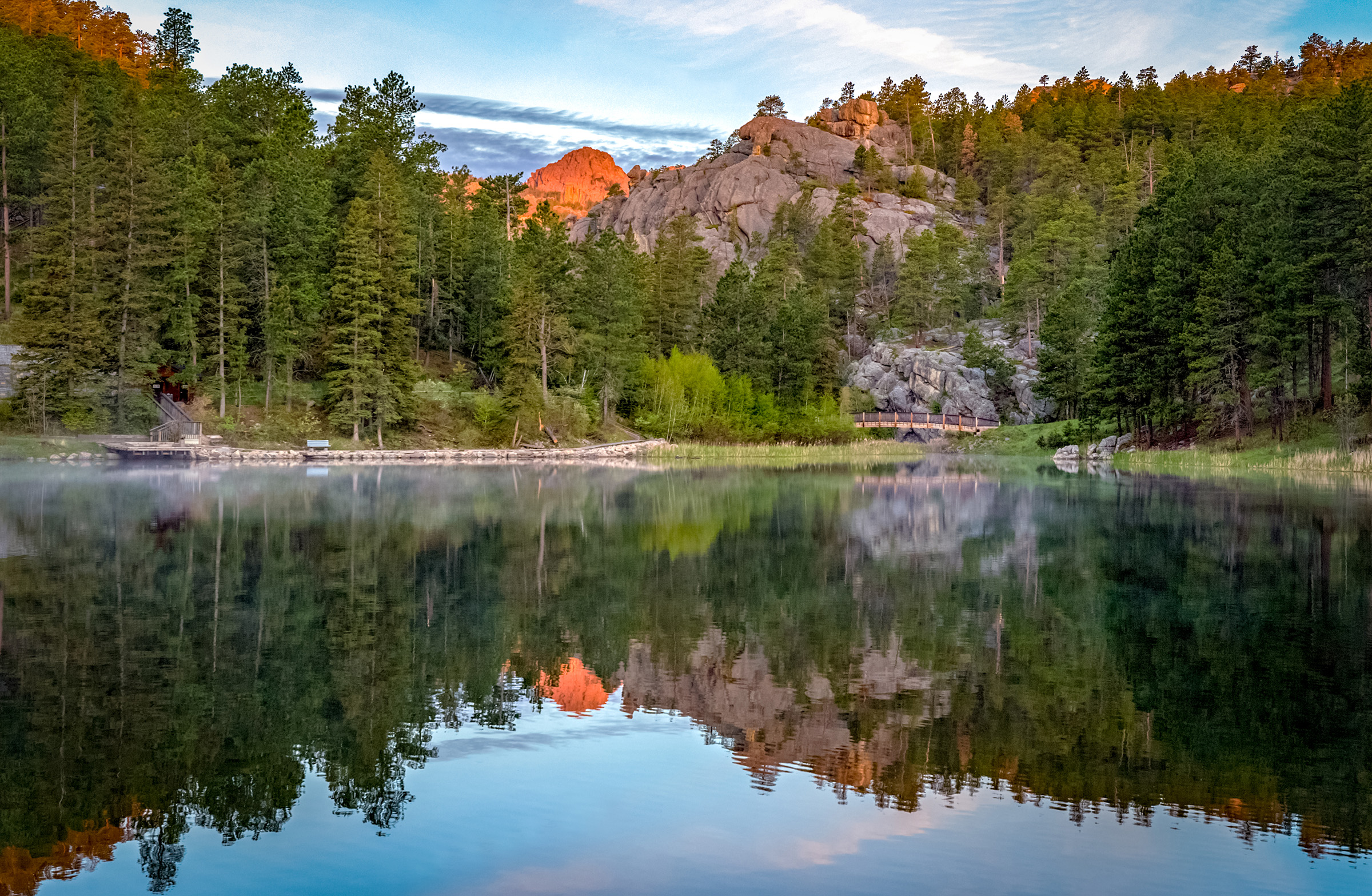 A lake overlooking pine trees and rocky mountains at Black Hills National Forest.