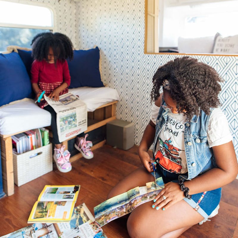 Two kids cutting out images to put on a dream board.