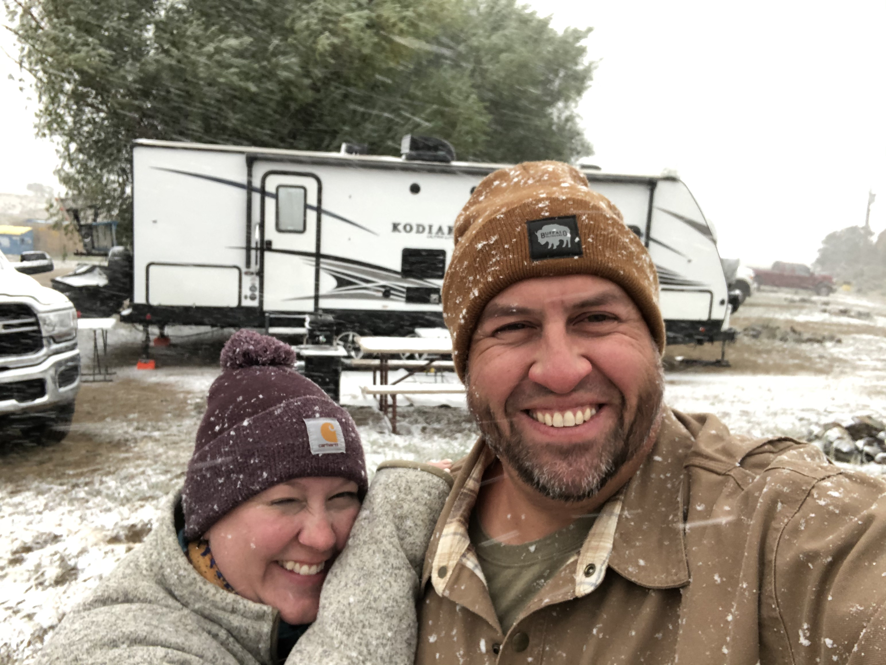 Abby Booth and her husband smile in the snow for a selfie in front of their Dutchmen Kodiak travel trailer. 