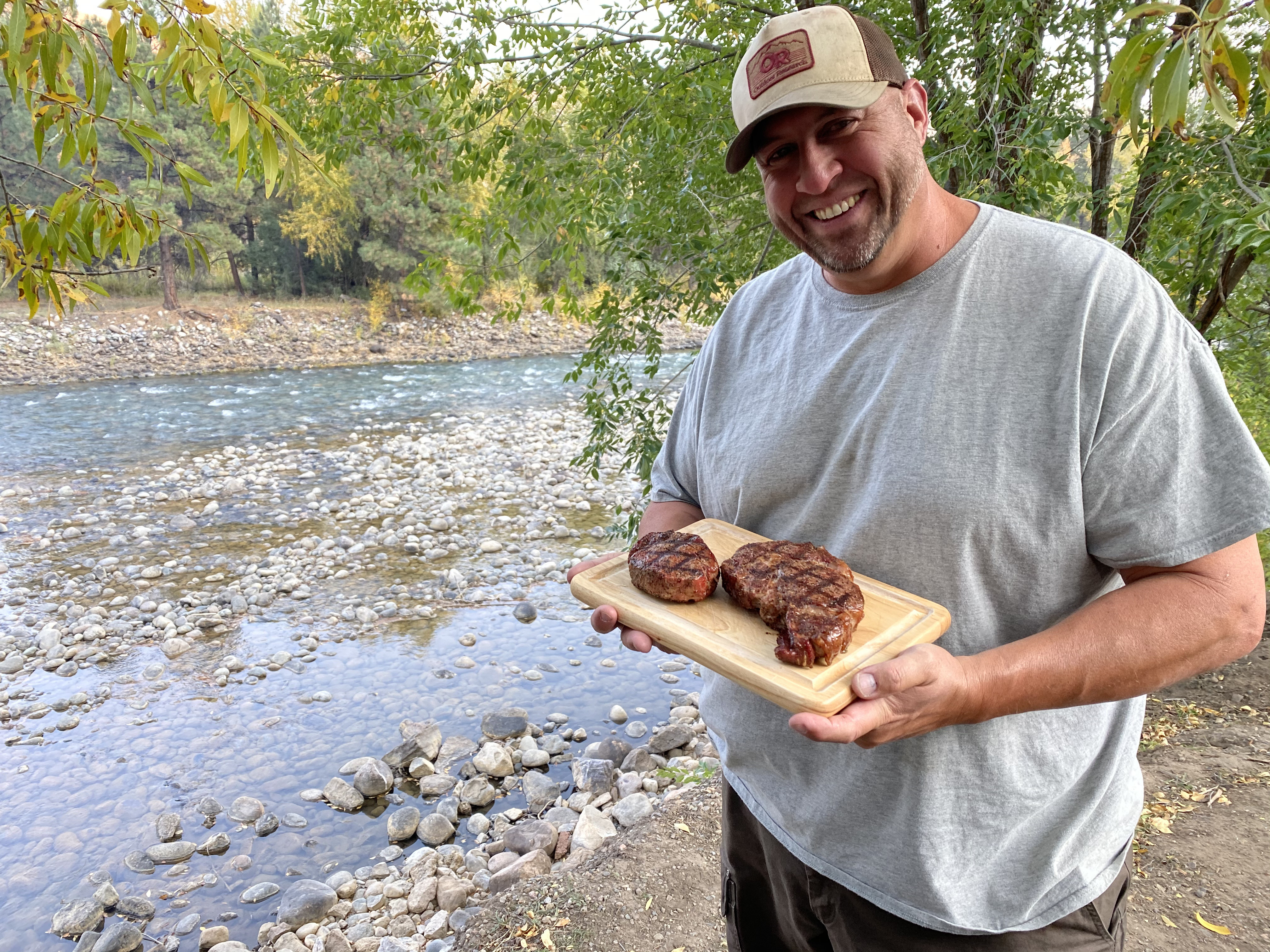 Abby Booth's husband holds a cutting board with steaks.
