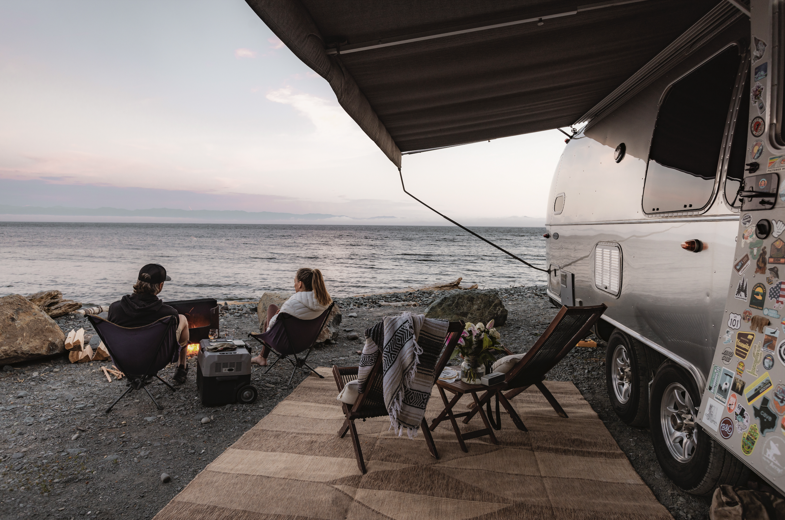 Karen and Lenny Blue sitting by the water outside their Airstream Flying Cloud