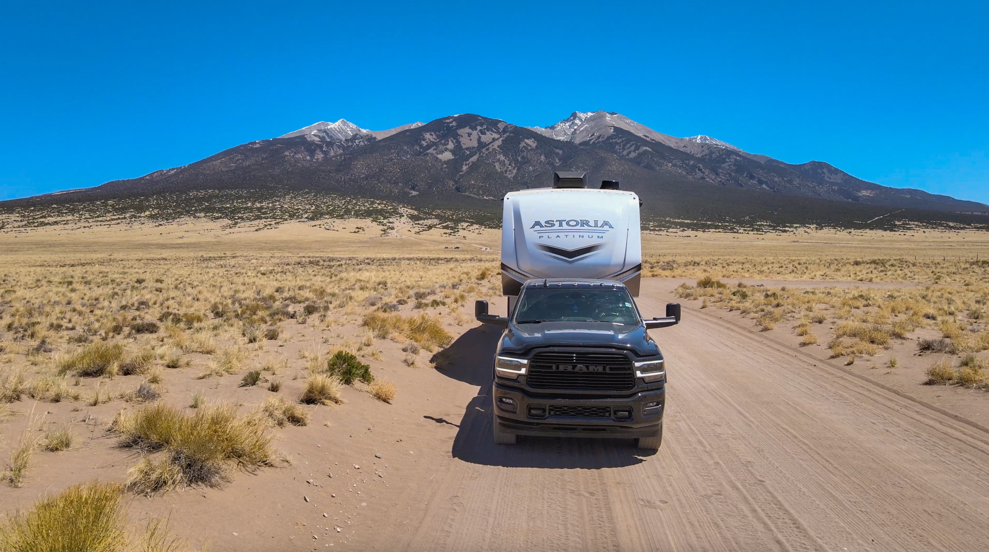 A truck tows Bailey and Nicole Damberg's Dutchmen Astoria Fifth Wheel on a dirt road in the desert.