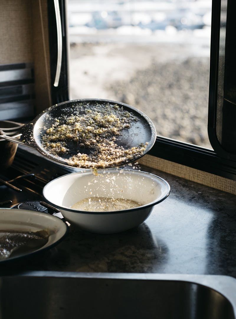 Zest and salt being poured over other seasonings in a bowl inn the RV kitchen. 