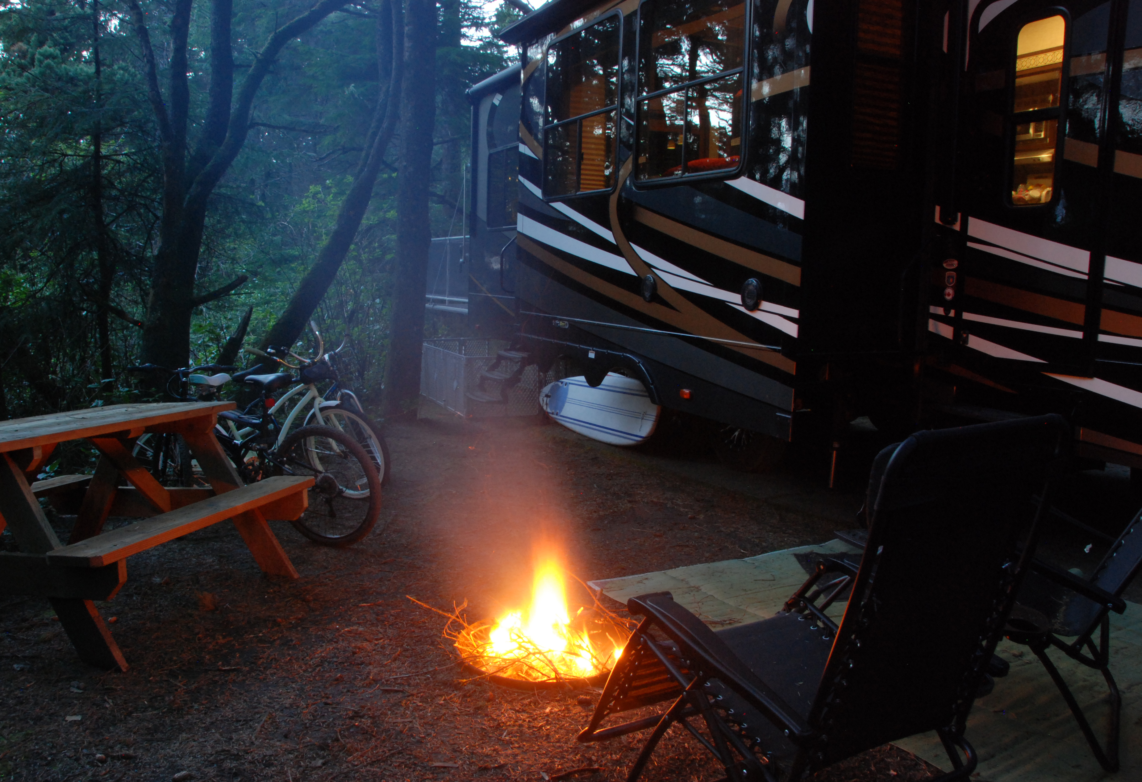 Eric Hannan's RV parked at a campsite next to a fire burning in a pit at night.