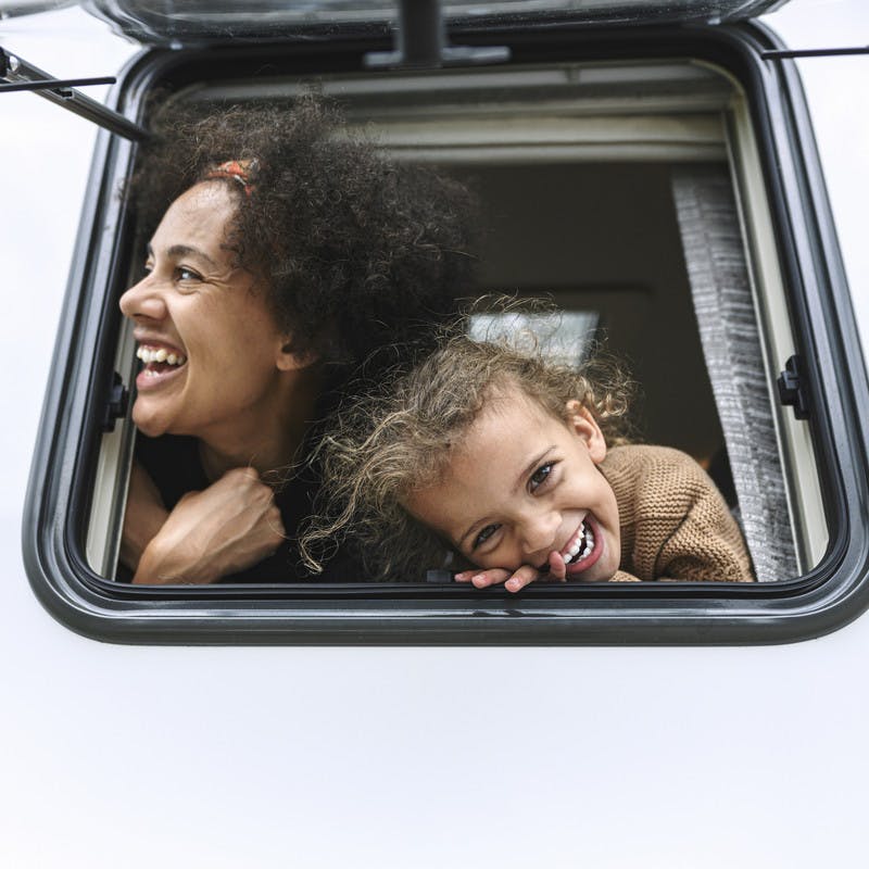 Mother and daughter poke their heads out of the window of their Class B RV by Hymer.