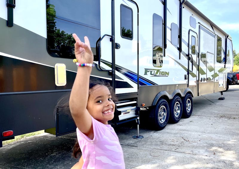 Robin and Warren Baxter's granddaughter throwing up a peace sign in front of their RV