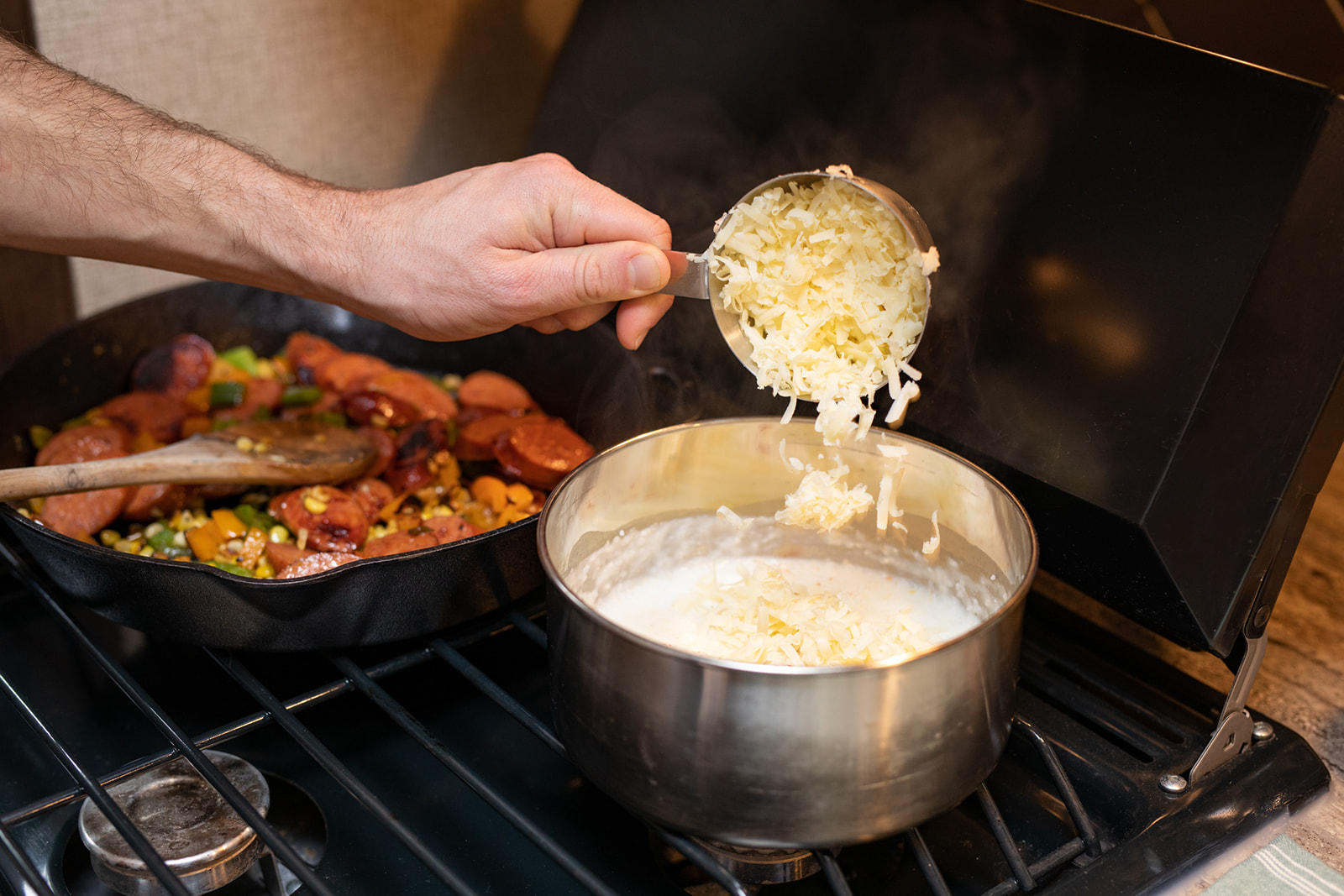 Adding shredded cheese into cooking grits on the stove.