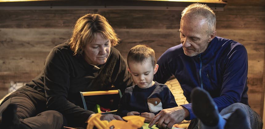 A young boy is cozied up on a RV master bed as his grandparents read to him.