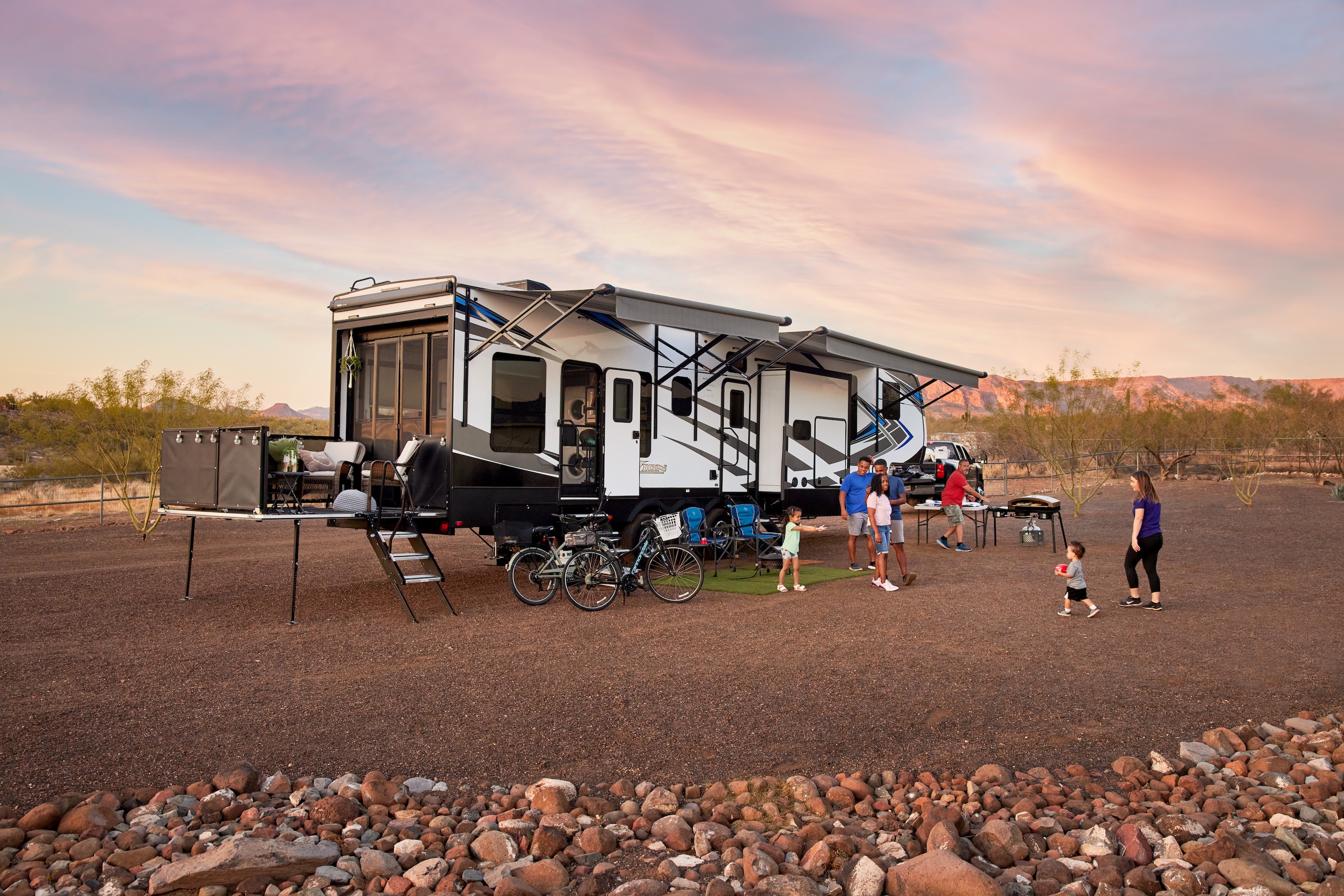 Robin, Warren and their family play outside of their Keystone Fuzion toy hauler RV.
