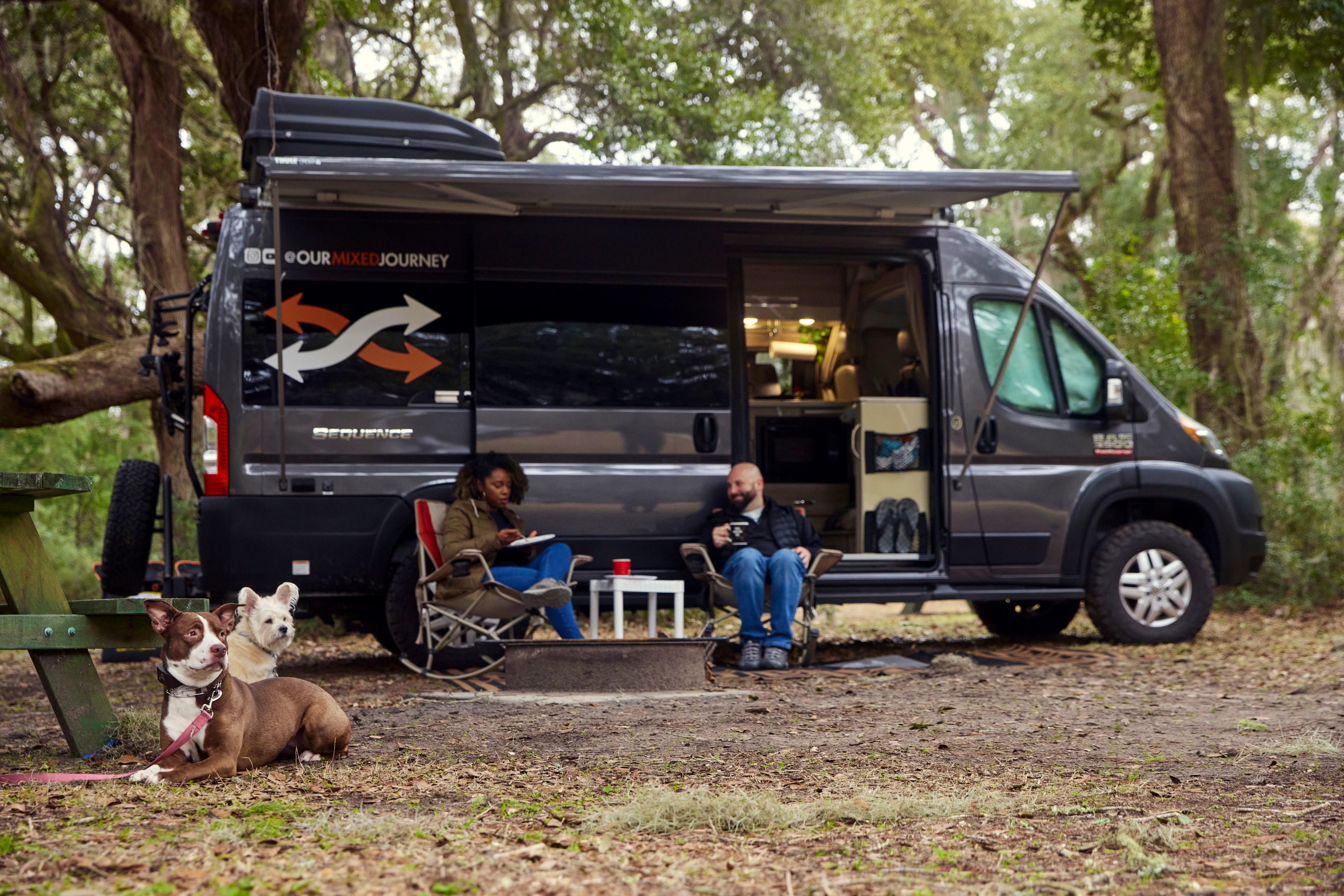 Gabe and Rocio Rivero sitting outside their RV with their two dogs