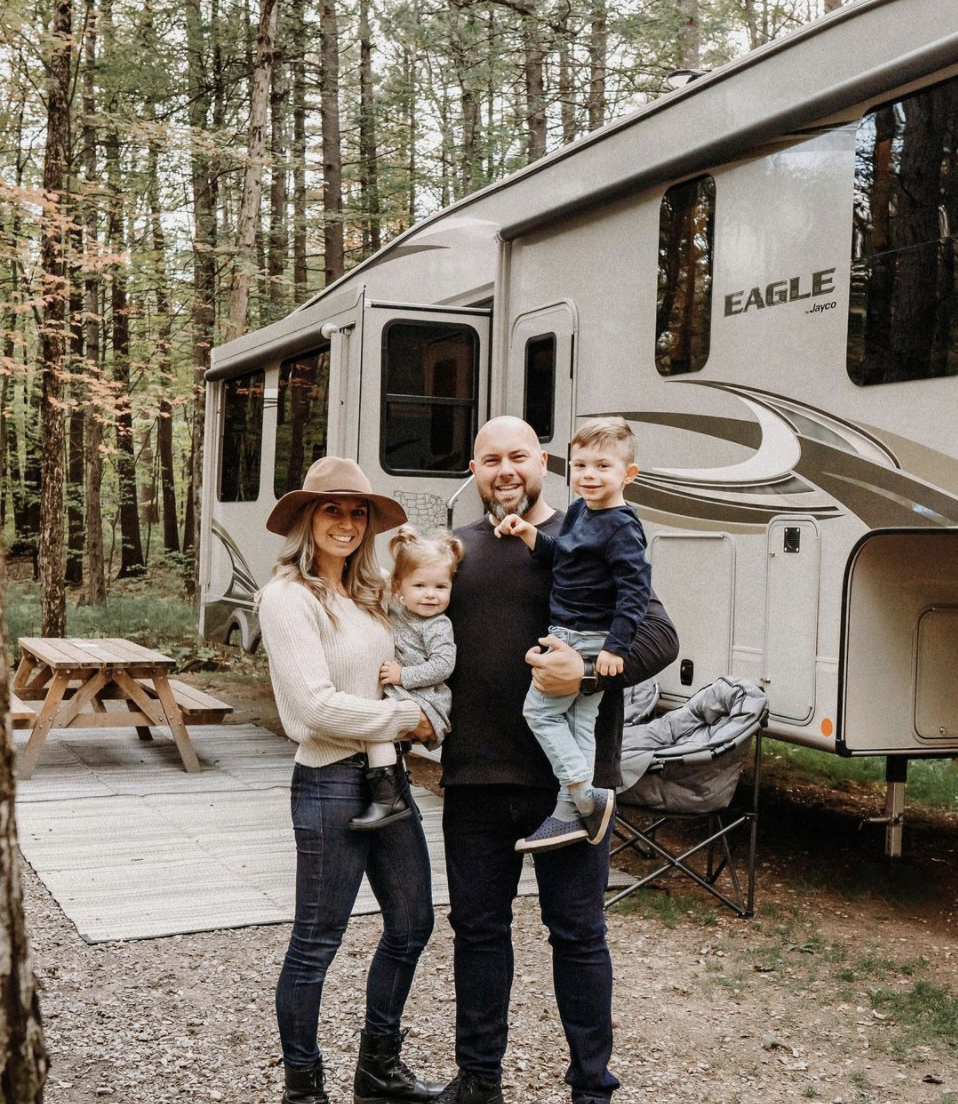 Max and Marie holding their children in front of their RV
