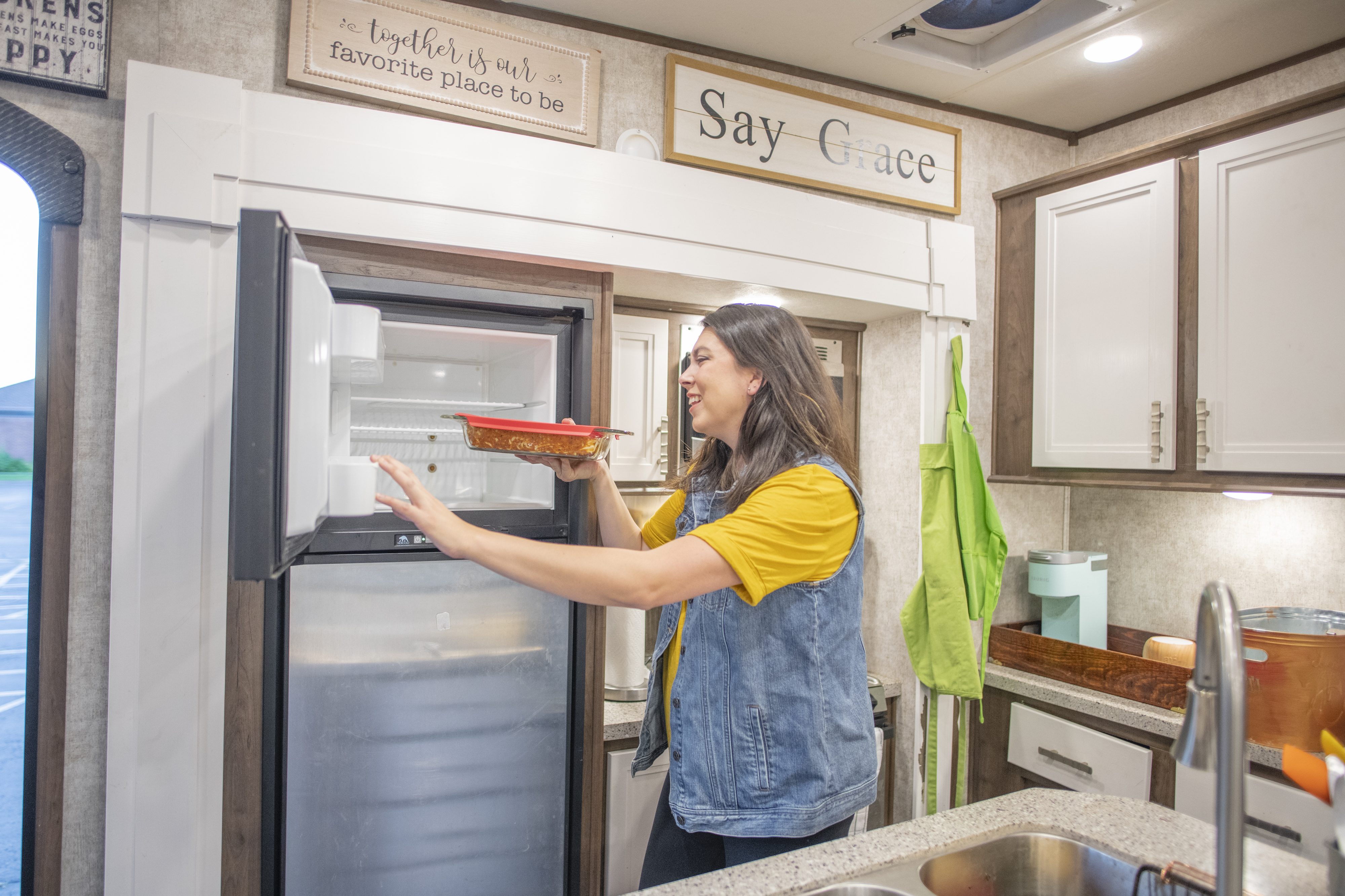 Chelsea Day putting a dish inside the freezer in her Highland Ridge RV.
