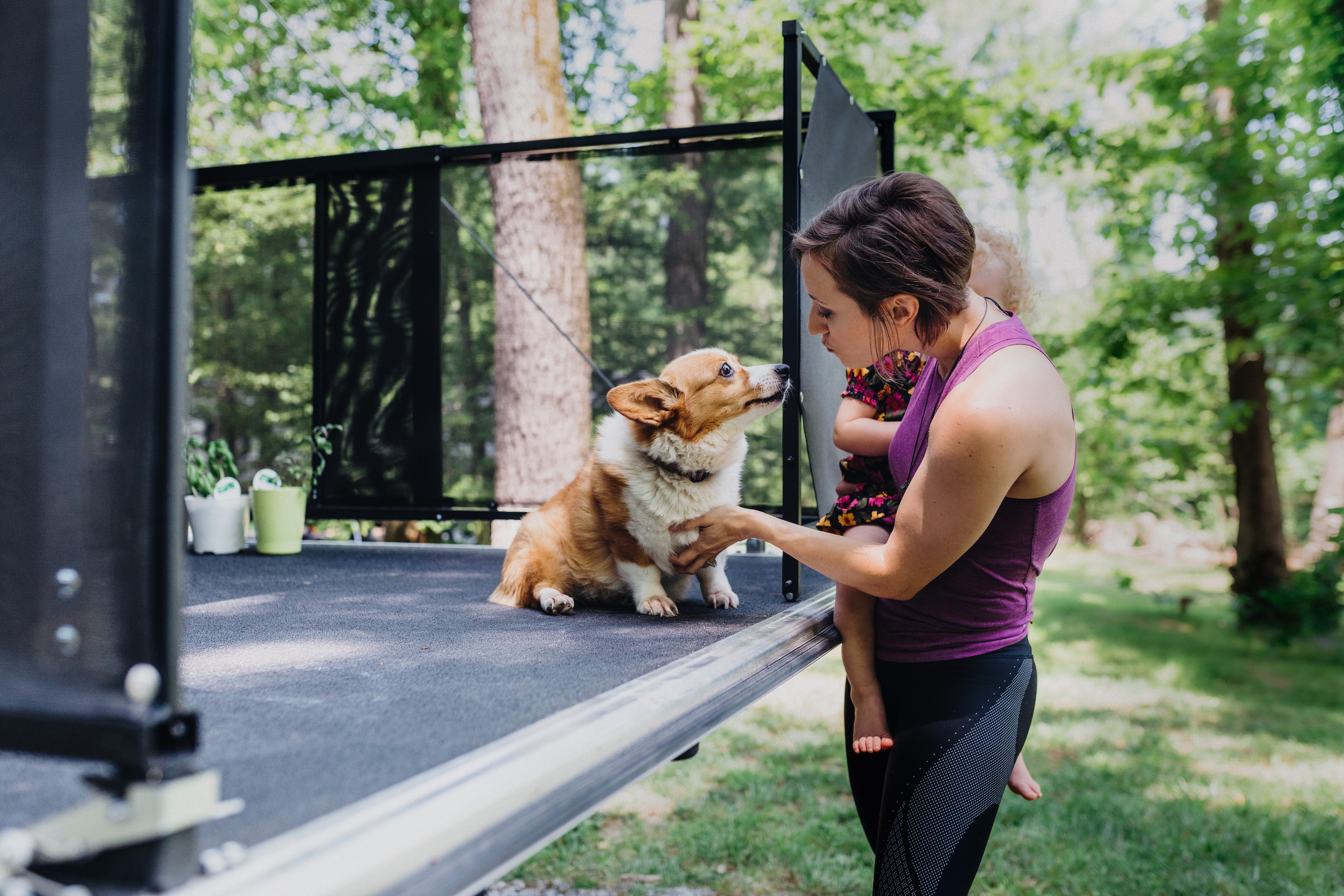 A woman pets a dog that is sitting on the patio of a toy hauler RV