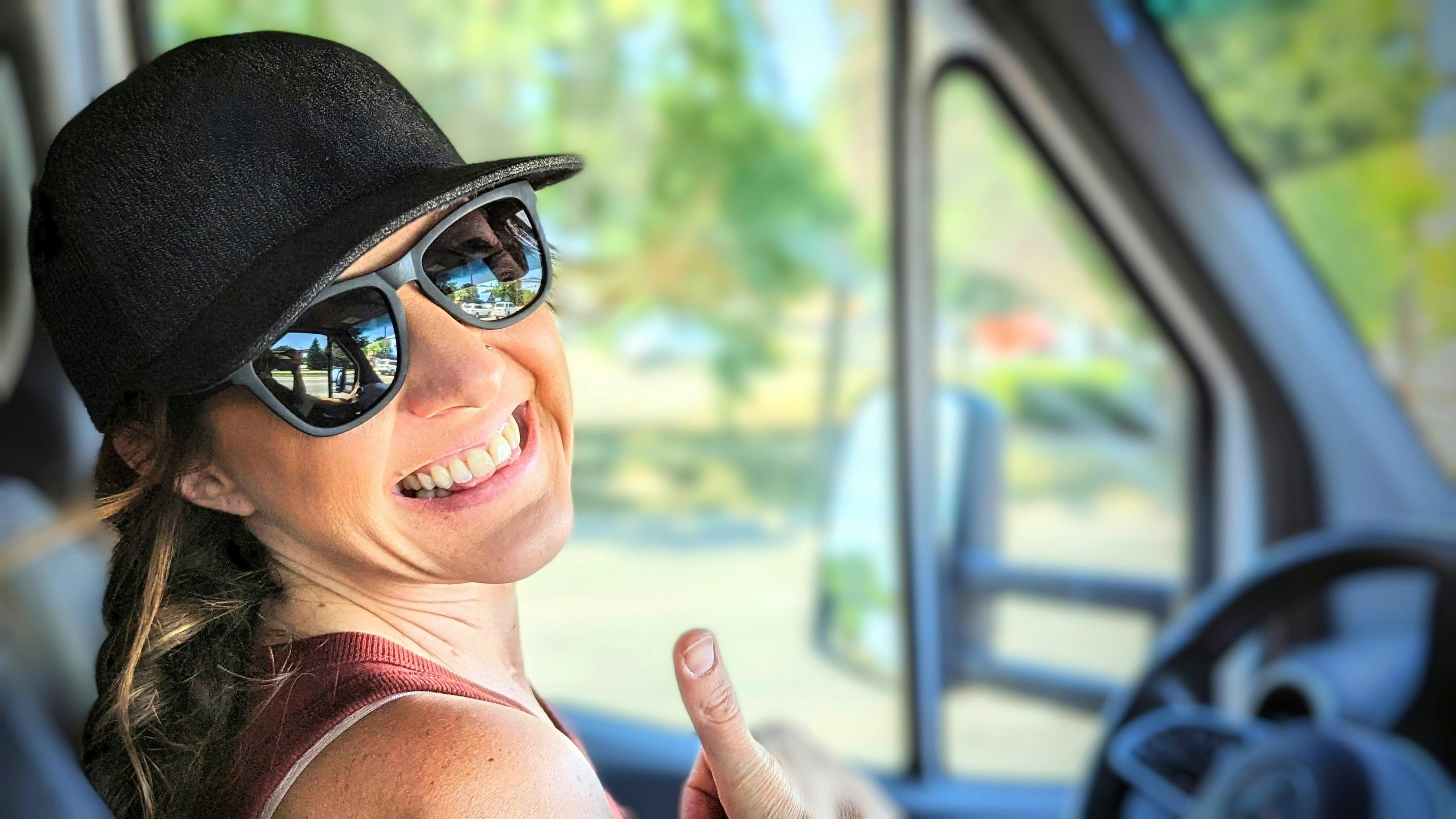 Sarah Bauer smiling and giving a thumbs up from the passenger side of their class C RV