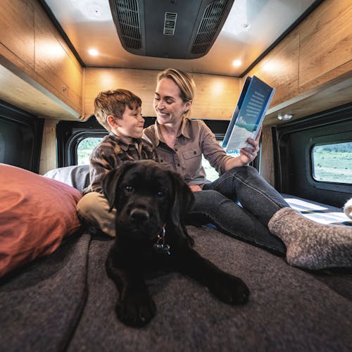 A woman, boy and puppy sitting in an Airstream Rangeline