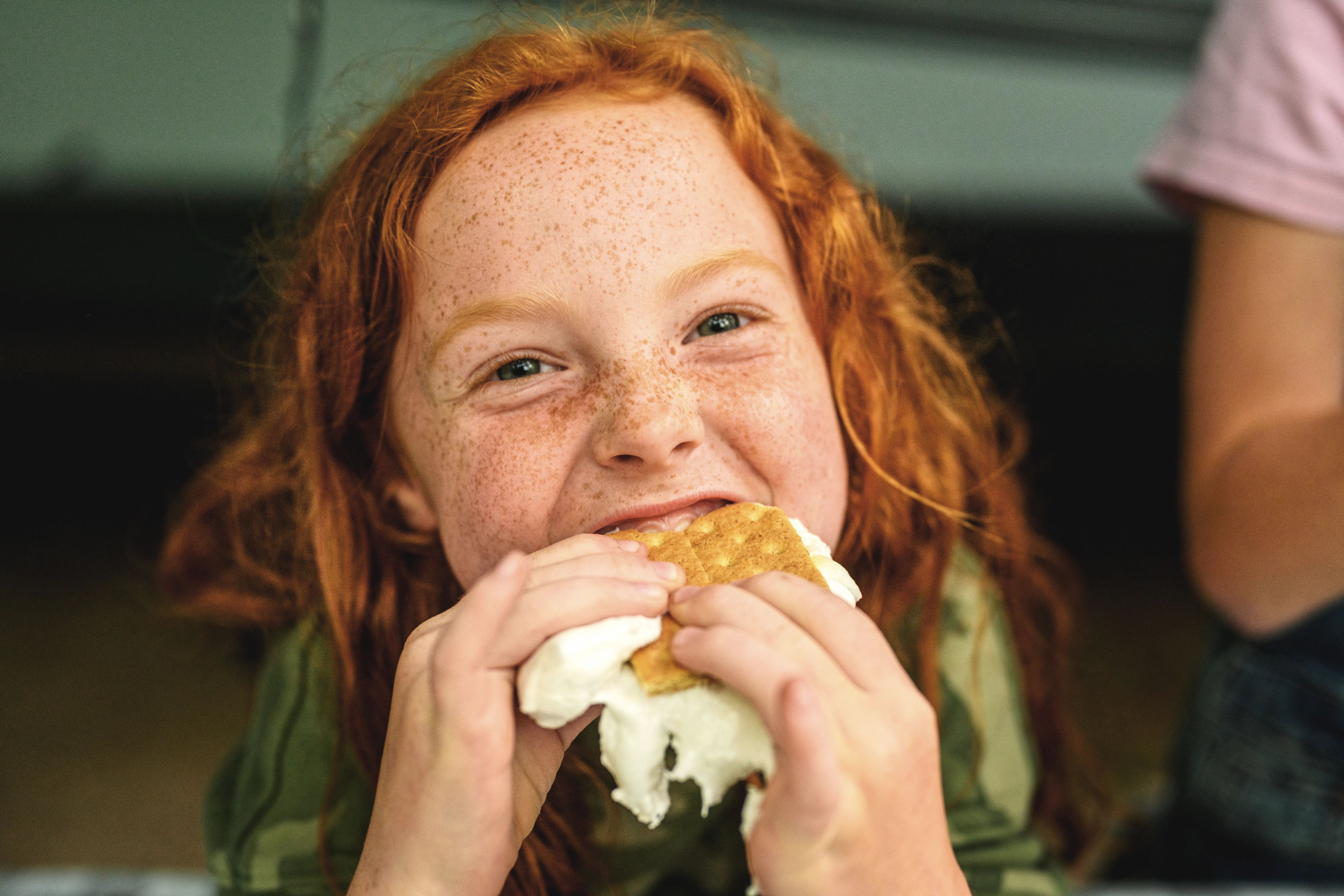 A little girl bites into a smore