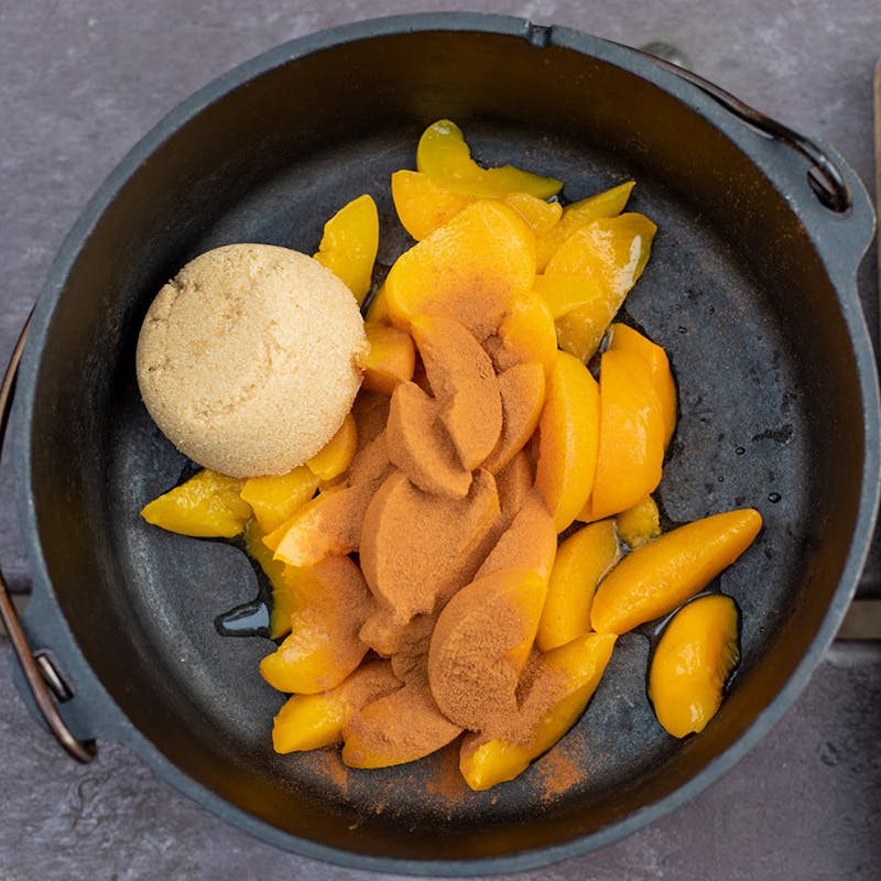 Peaches in a dutch oven with brown sugar and cinnamon.