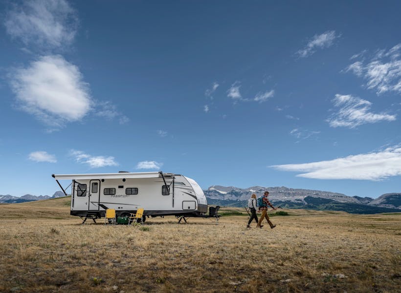 A couple hiking away from a keystone passport travel trailer