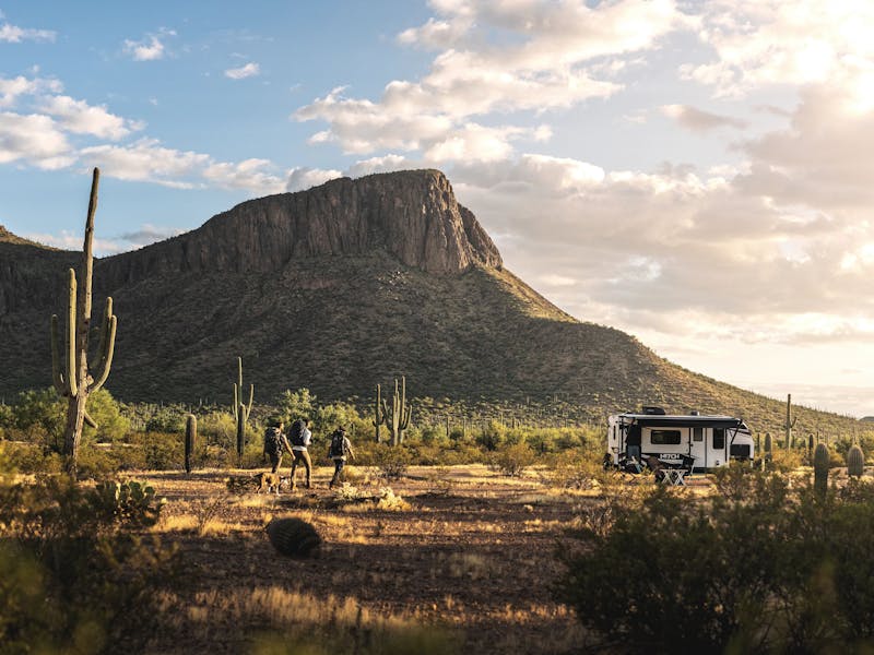three men walking towards a Hitch travel trailer in the Arizona dessert