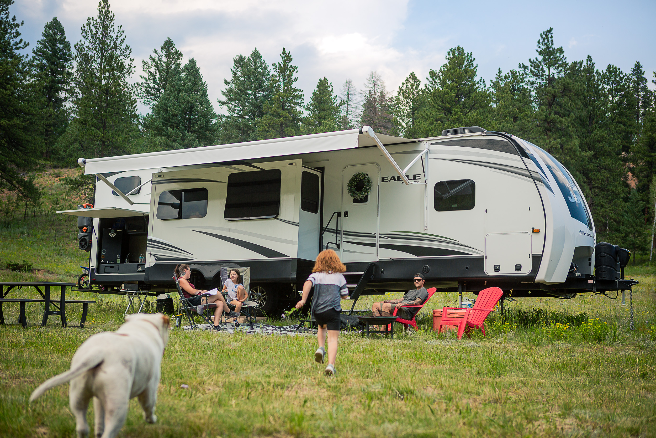 Ila Roberson running towards her family sitting outside their Jayco Eagle 