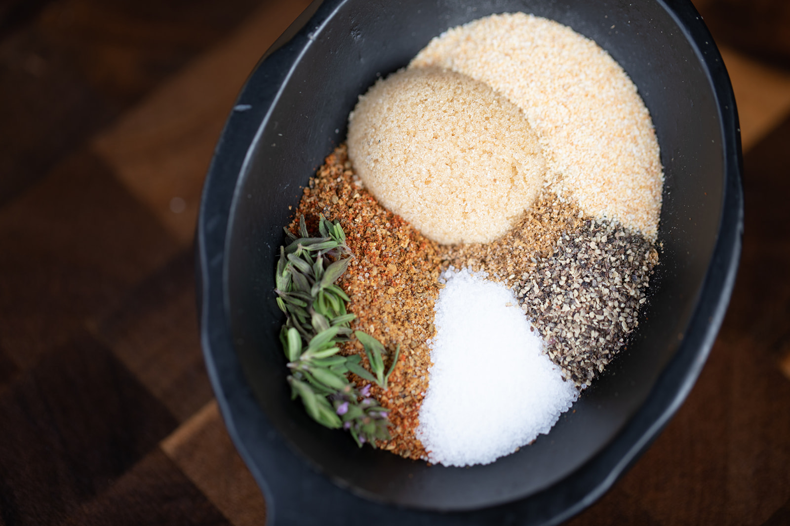 A bowl of herbs and spices in pretty piles in a bowl. 